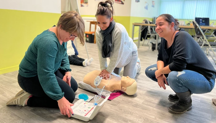 Stagiaires s'exerçant sur un mannequin de secourisme équipé d'un défibrillateur, guidés par leur formatrice